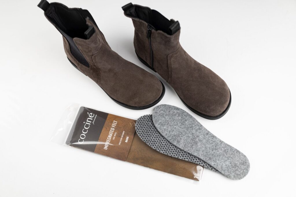 Wkładki do butów z filcu Coccine obok damskiego obuwia